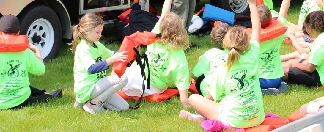 Student sitting in the grass and raising their hands 